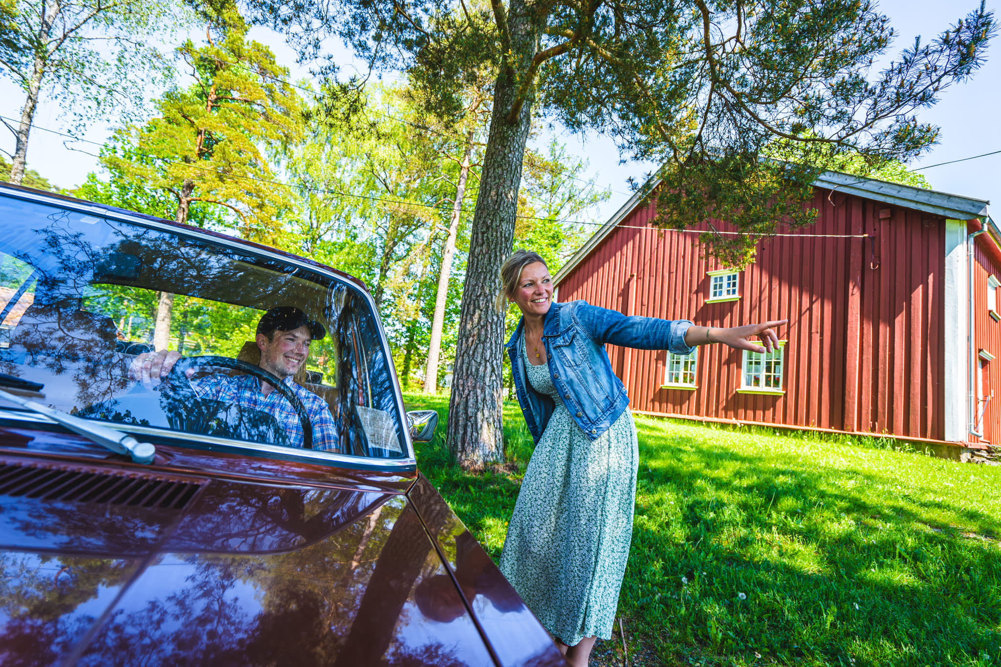 Dame peker ut veien for en bil som kommer forbi på bygdetunet