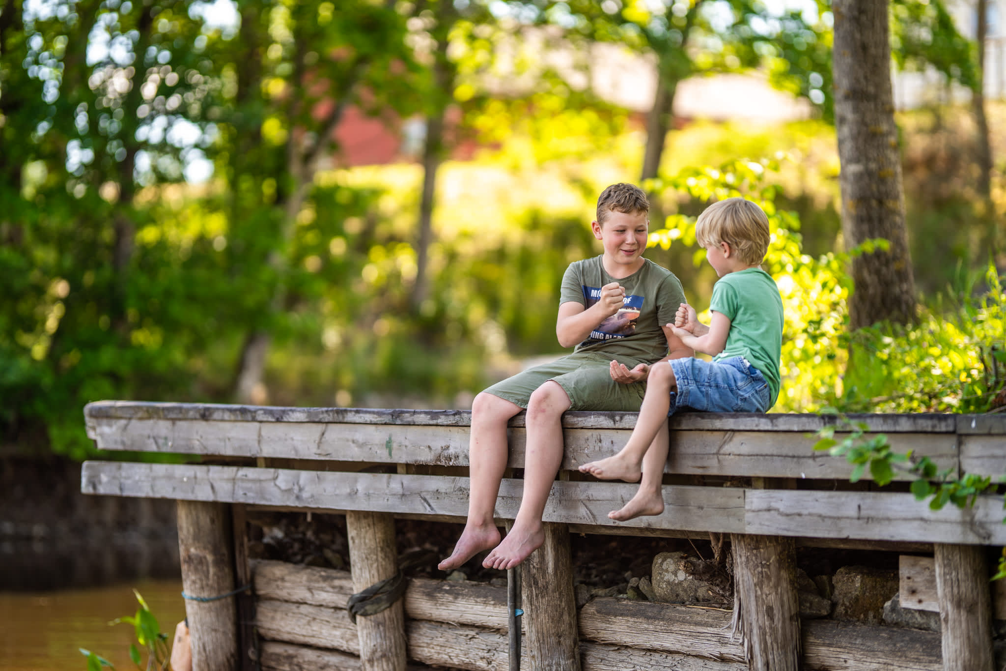 To gutter som sitter på en brygge og leker stein saks papir
