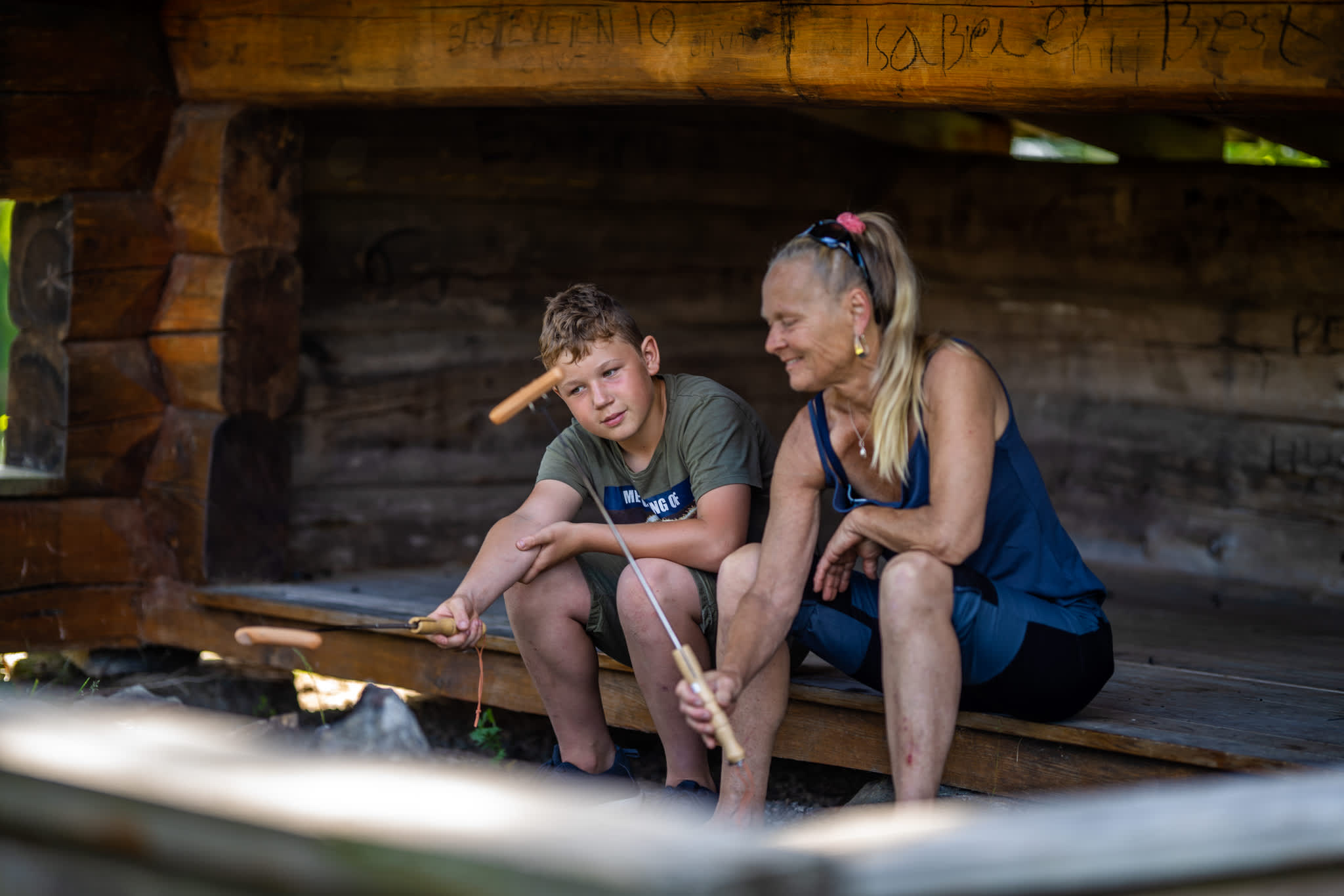 En dame og en gutt som griller pølser i gapahuken