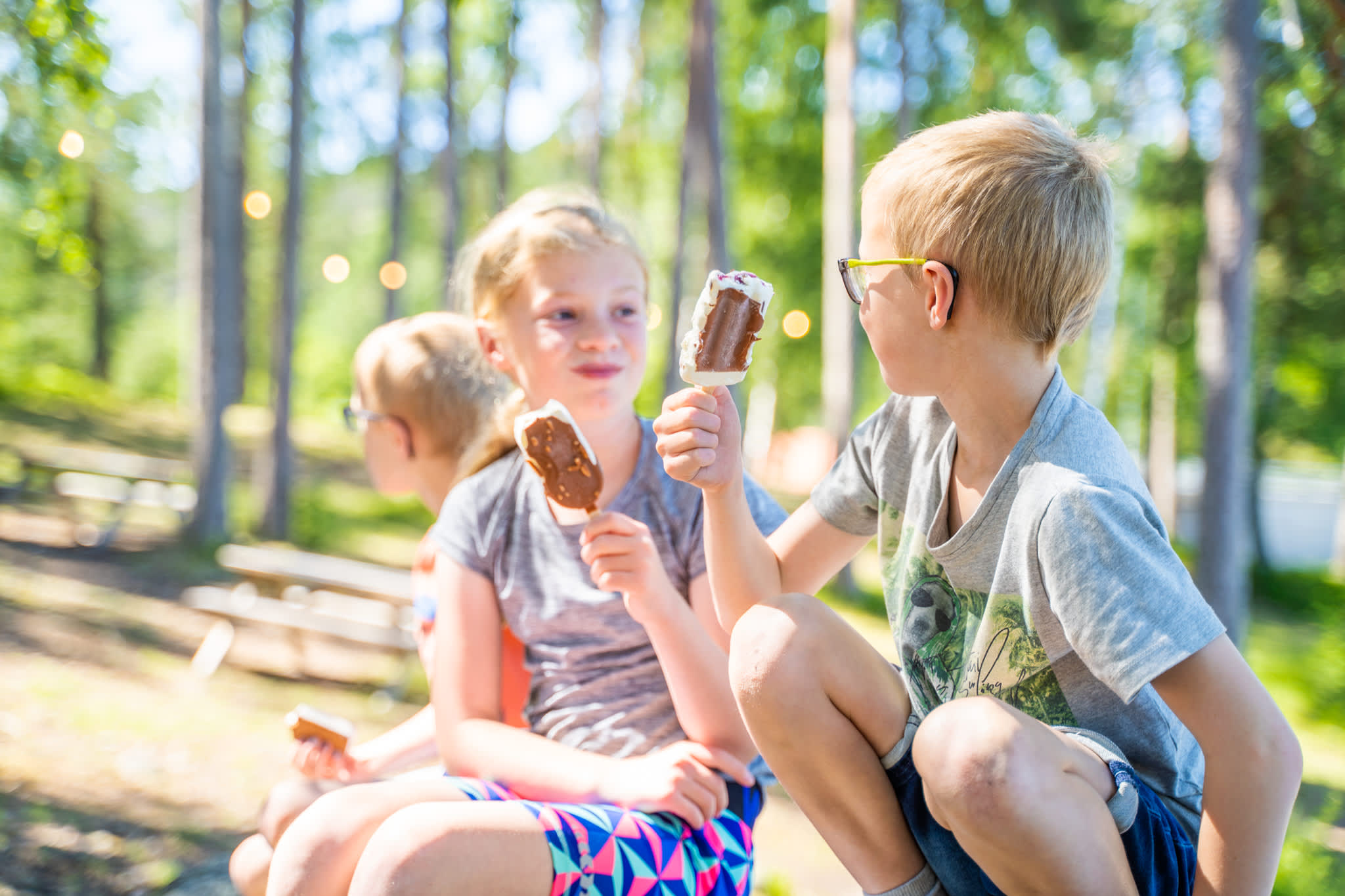 Tre barn sitter og spiser is