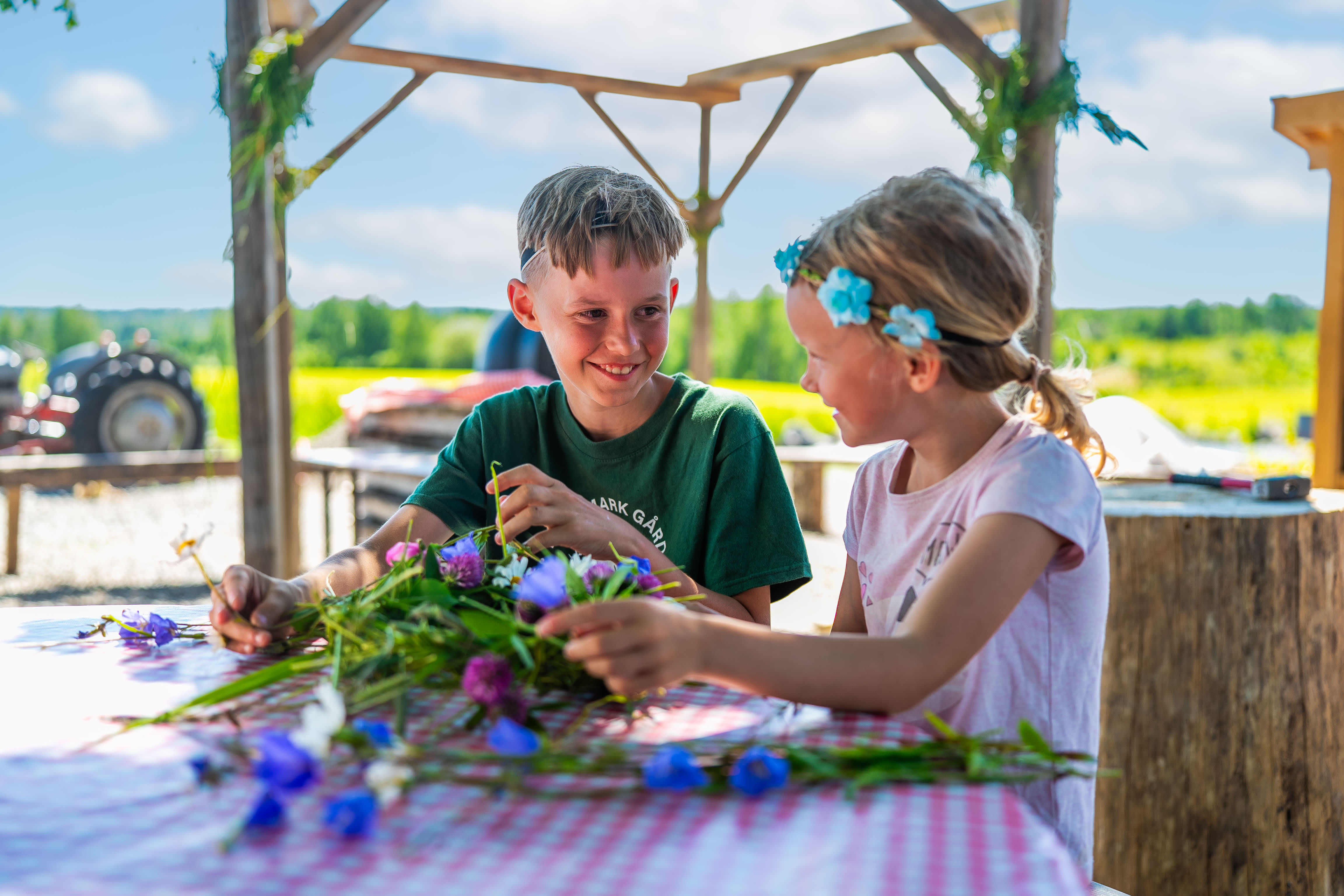 To barn som binder sommerkrans på bondegård