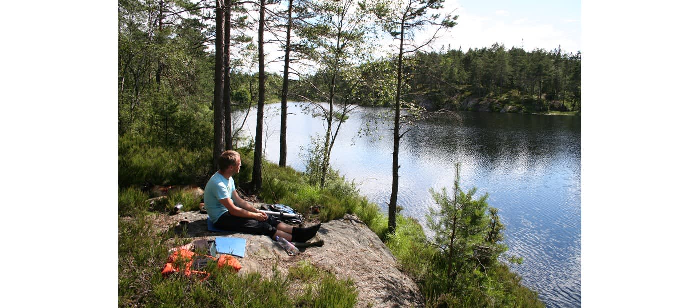 En gutt som sitter ved ett vann og titter utover