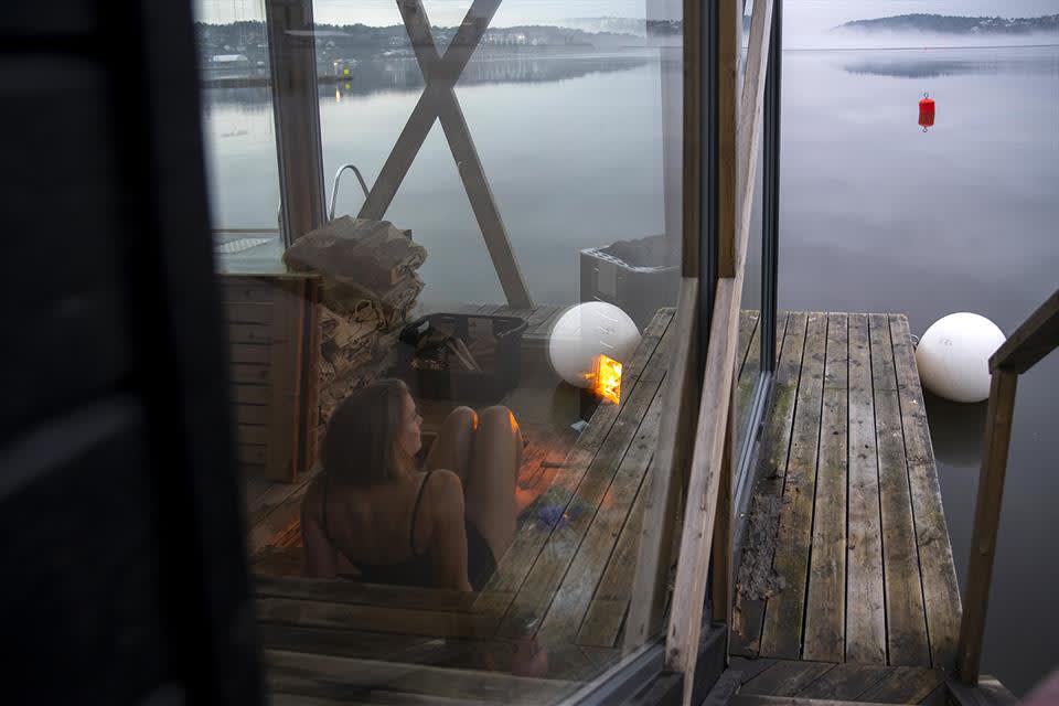 Kvinne sitter i en flytende badstu og ser utover vannet