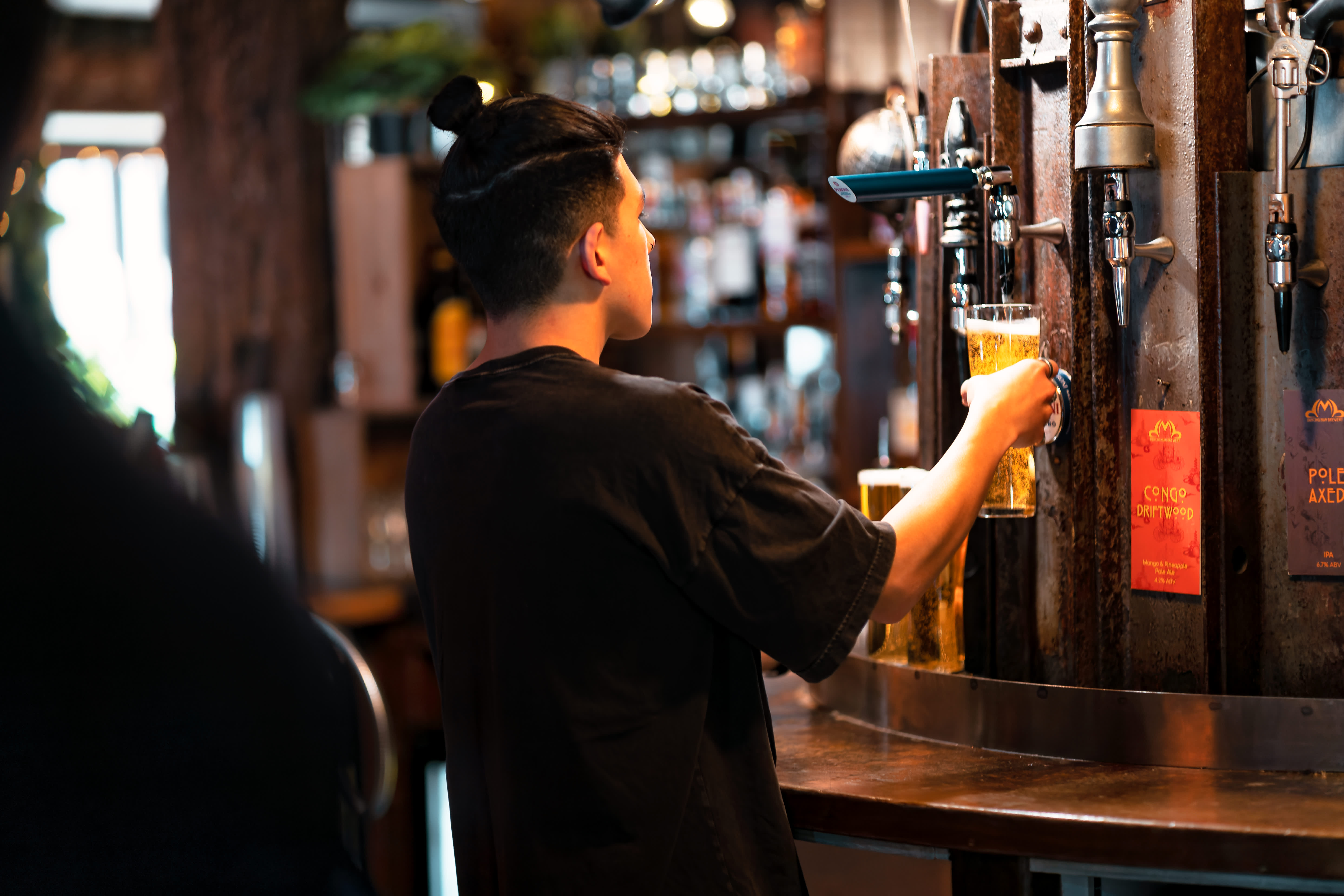 Bartender pouring a pint of draft beer at the Dancing Man Brewery