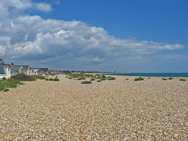 View of Pagham Beach on a sunny day with beach houses overlooking the beach on the left hand side
