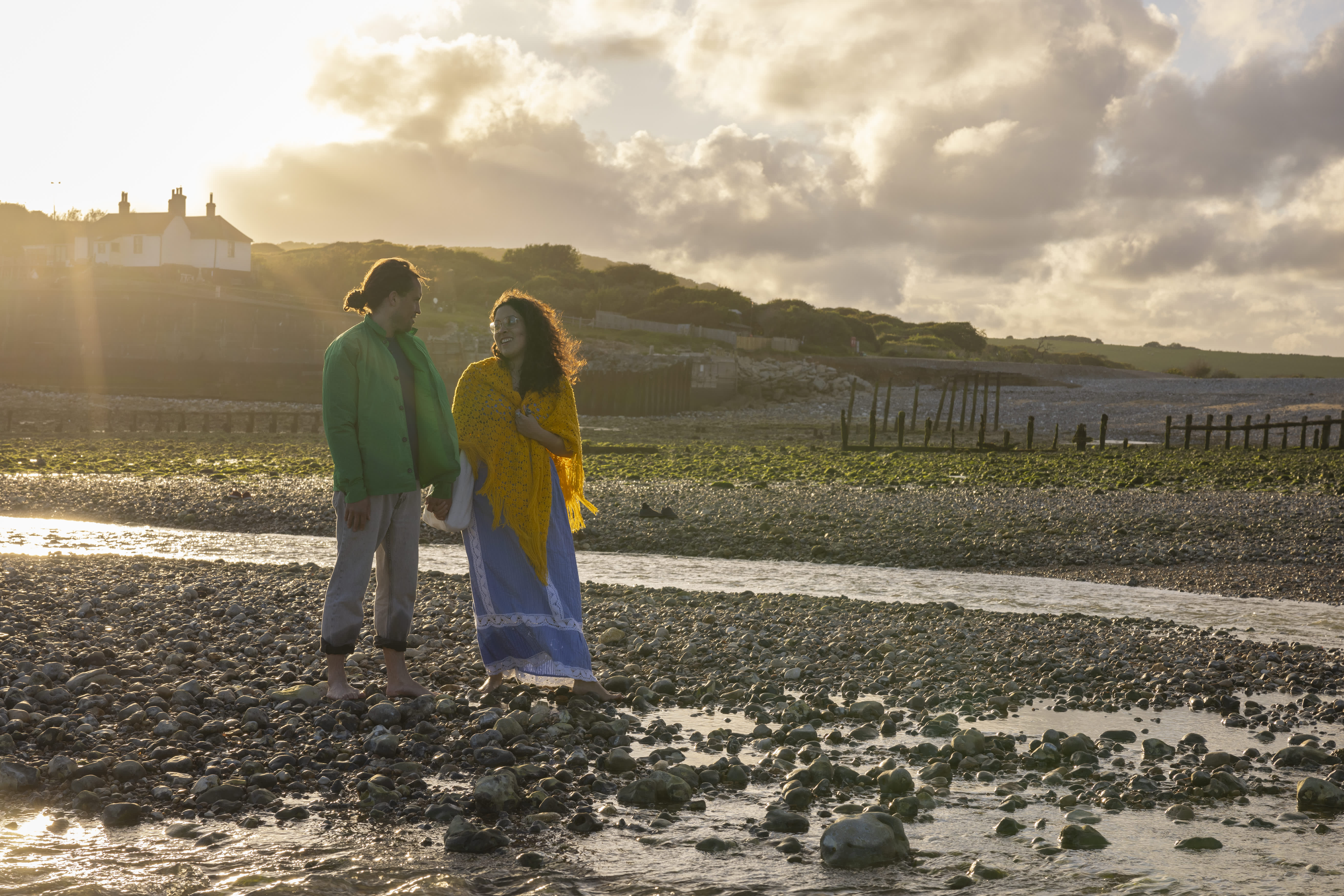 A couple stand on the rocky shore at Cuckmere Haven near Seaford Head, Sussex