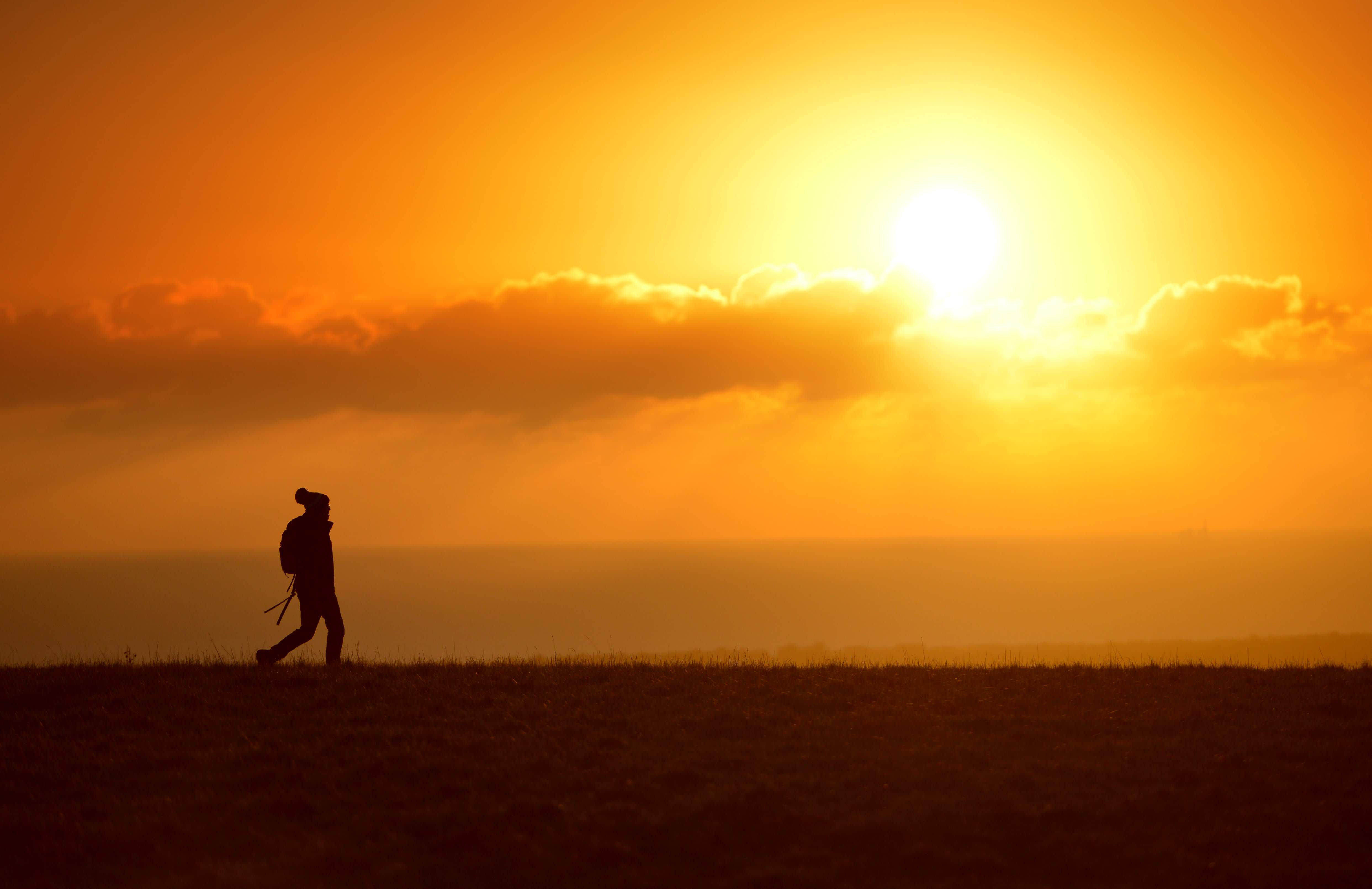 A lone walker on the South Downs in Sussex at sunset