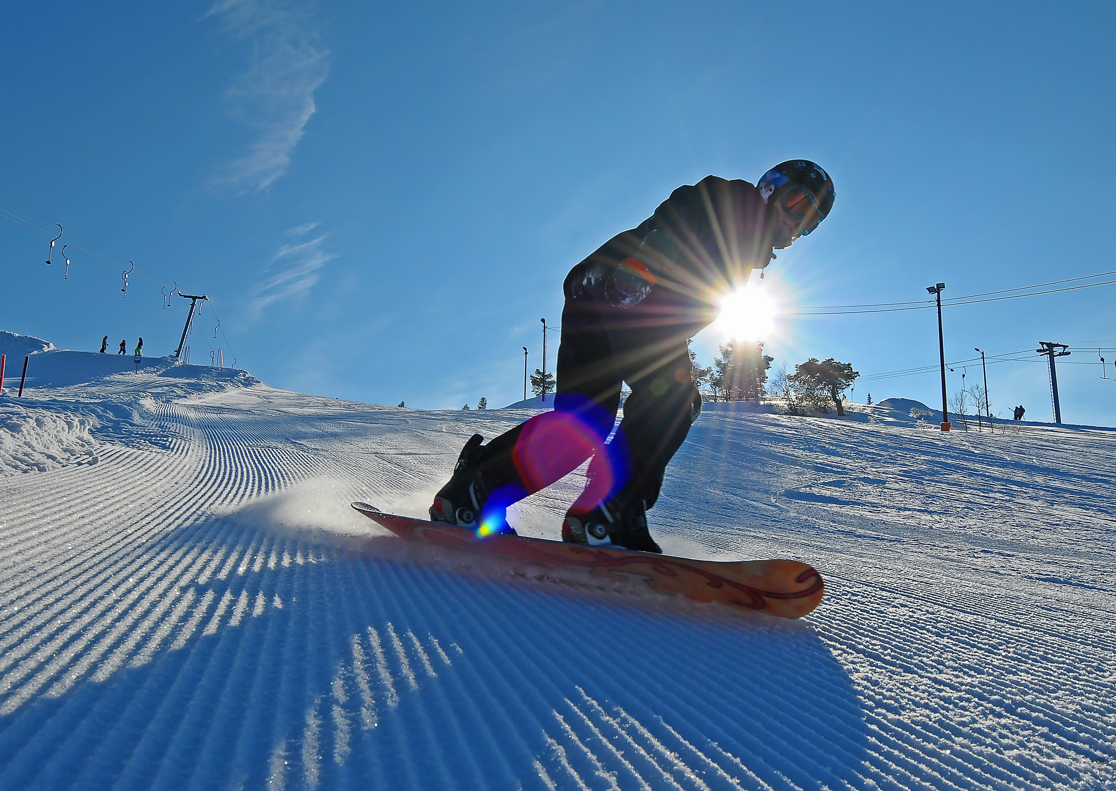 snowboarder i nypløyd bakke med sol og blå himmel i Setesdal