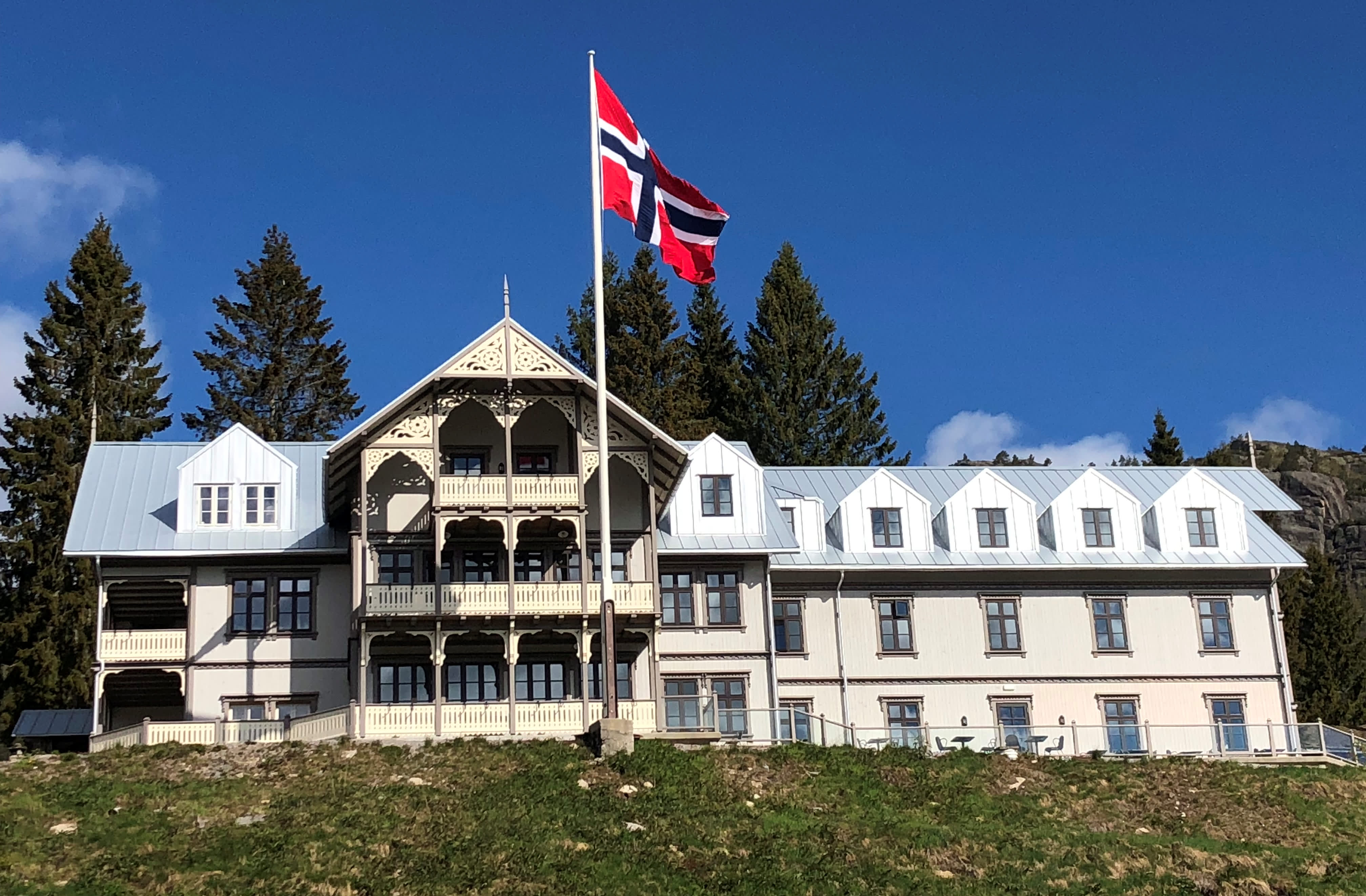 Hotel in an old building style and a flagpole with the Norwegian flag. Photo