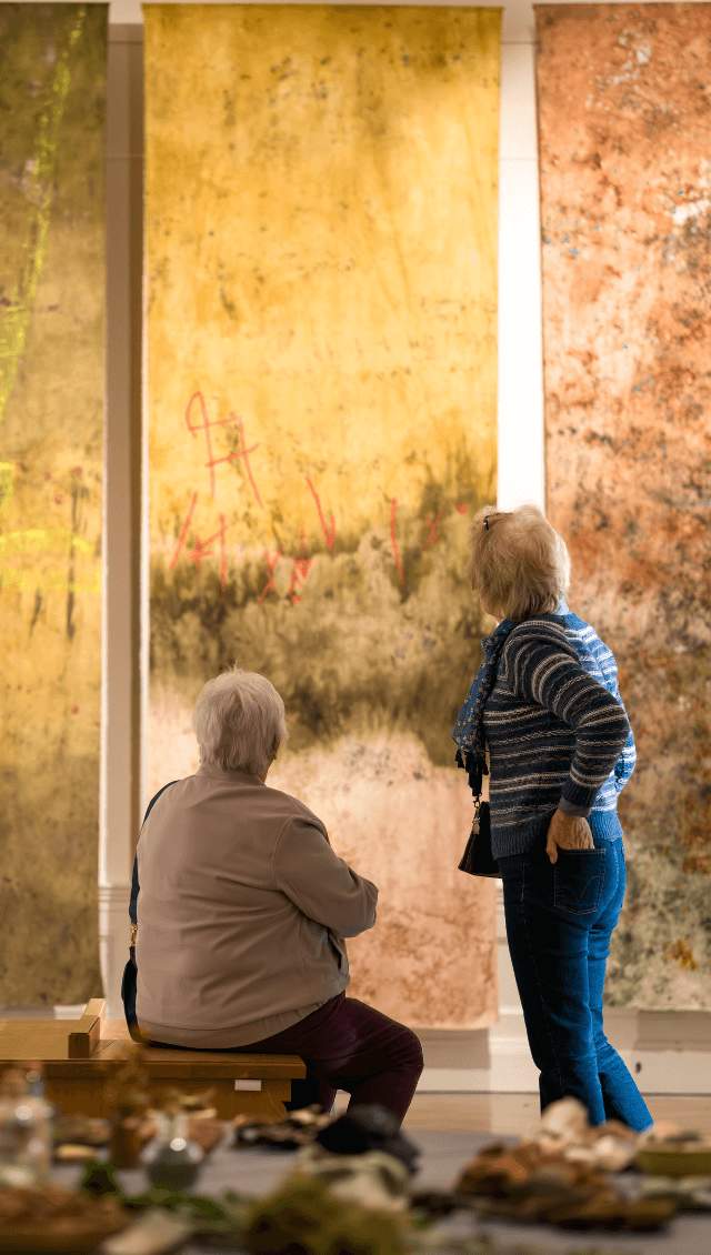Two women look at an art installation of Un/Earthed
