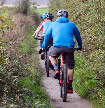 Cyclists riding along a dirt path next to fields