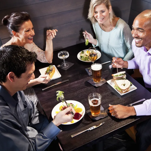 Two couples eating, drinking and talking in restaurant.