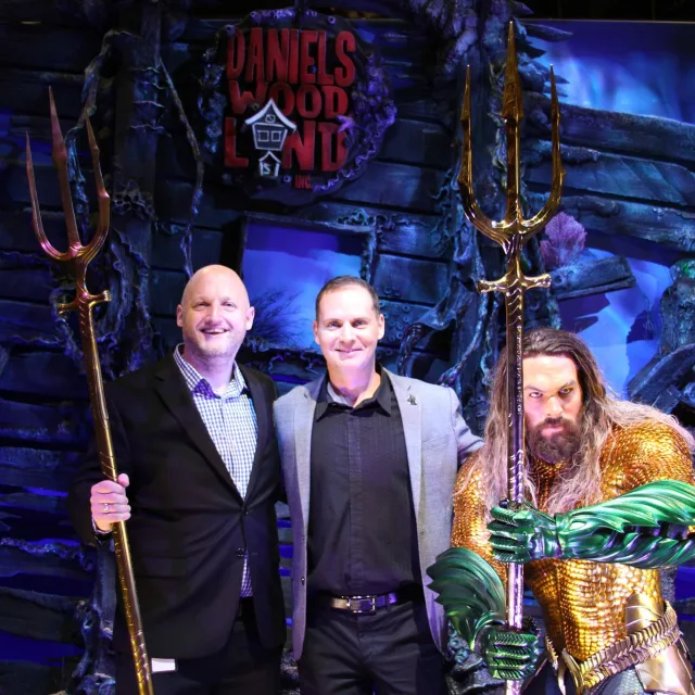 James Paulding and Andy Dautermann speak alongside Aquaman wax figure at IAAPA press conference.