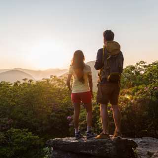 A couple watches the sun setting behind the western mountains from atop Craggy Gardens.