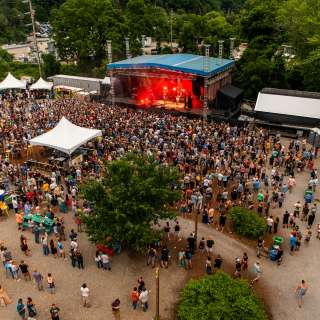Aerial photo of a crowd surrounded outside near a stage at Salvage Station