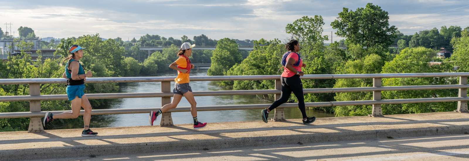 Three women running across a bridge in West Asheville