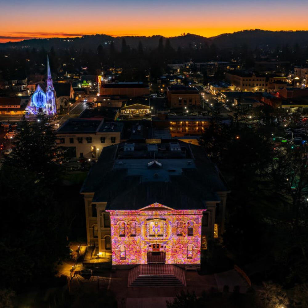 Aerial view of Downtown Napa at night with several buildings lighted with art