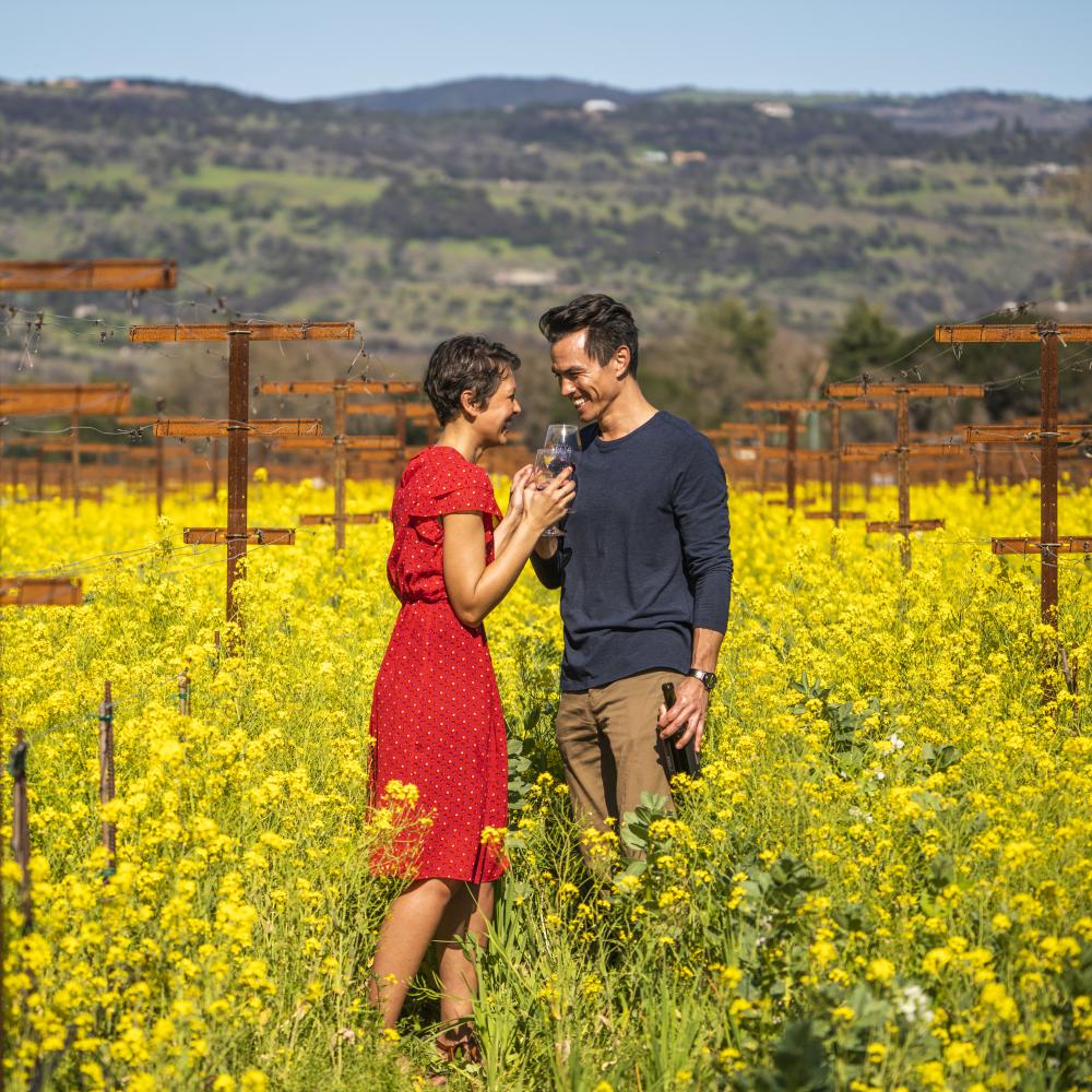 A couple enjoys wine among the wildflowers at Robert Biale Vineyards in Napa Valley