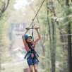young smiling girl on zipline sails through muskegon state park forest