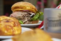 A large roast beef sandwich is surrounded by other food items which are out of focus.