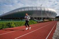A woman running on a track surface in front of Hayward Field.