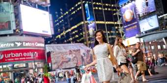 A woman walks with shopping bags outside the Eaton Centre shopping mall at night