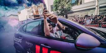 A passenger leans out of a purple car