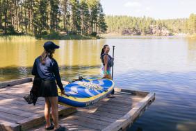 family carrying a paddle board down the dock to the waters edge in the black hills of south dakota