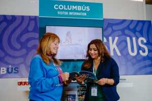 Experience Columbus staff member showing convention attendee a Columbus Visitor Guide at the Greater Columbus Convention Center