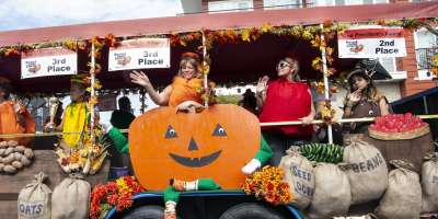 Women and girls dressed as a pumpkin, tomato, corn and potato on a float