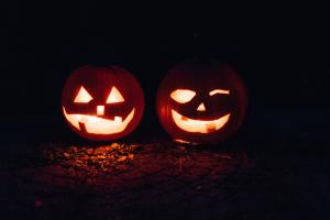 Two jack-o-lanterns glow in candlelight on an October night.