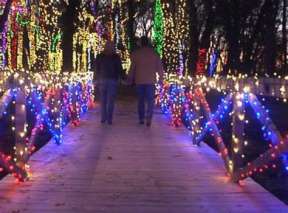 Two people walk holding hands through the path of lights at A Country Christmas at Fulton Valley Farms
