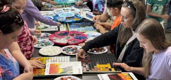 A group of folks assemble mosaic tiles for a larger community art project in San Marcos, Texas.
