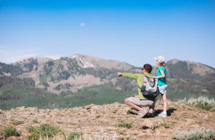 Father and young daughter looking at view from top of mountain