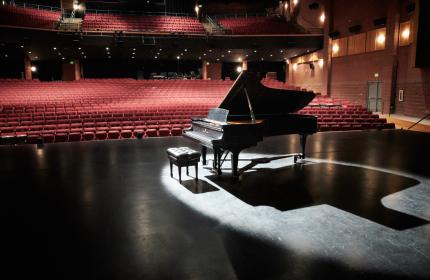 Photo of a piano in an empty theater