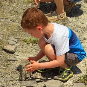 Boy bent down looking at rocks at Caesar Creek Lake