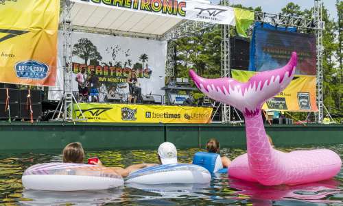 4 people in a lake on floats watching live music