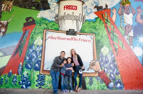 Family of four posing infront of the mural in the Rail District