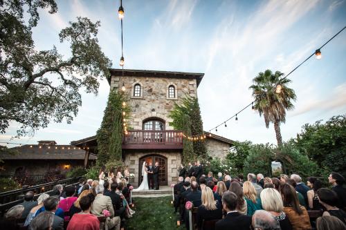 Man and woman standing at alter in front of the doors to a winery with guests