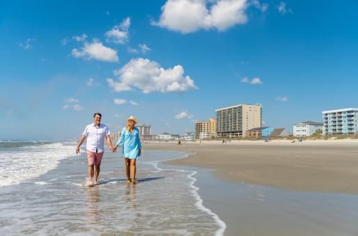A couple walks down the beach on a beautiful day in NMB.