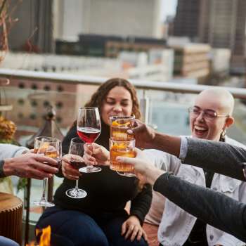 Groups of people clinking cocktail glasses on rooftop bar