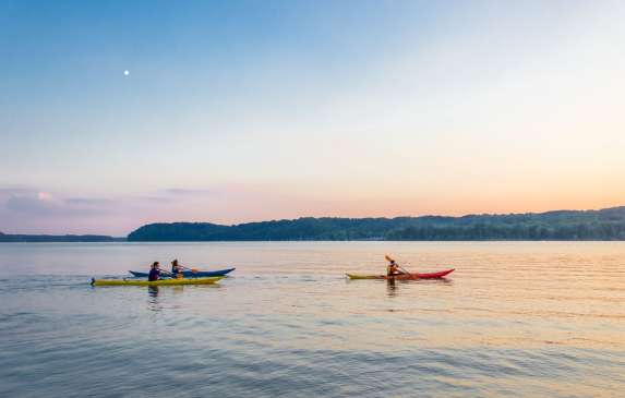 Three kayaks on Monroe Lake during sunset