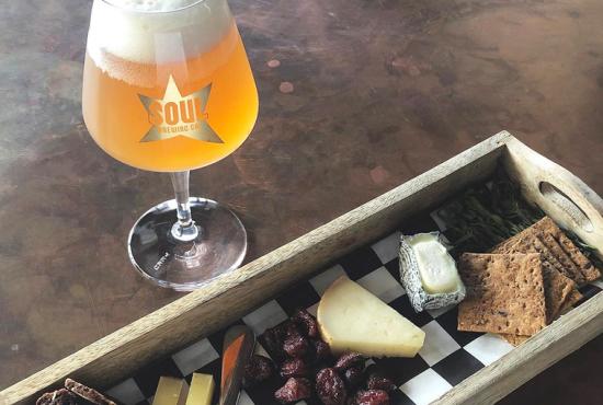 A glass of Soul Brewing Company beer with a platter of cheese.