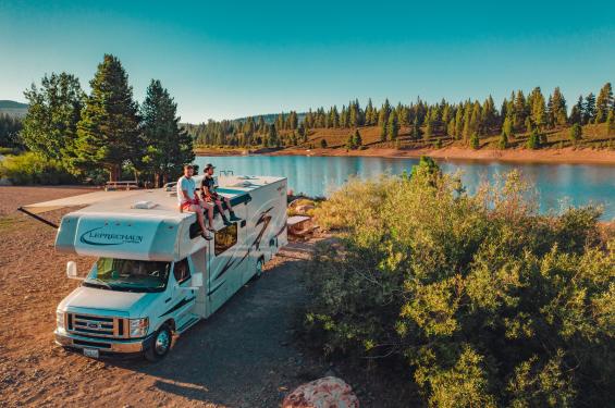 Friends sitting on RV by lake