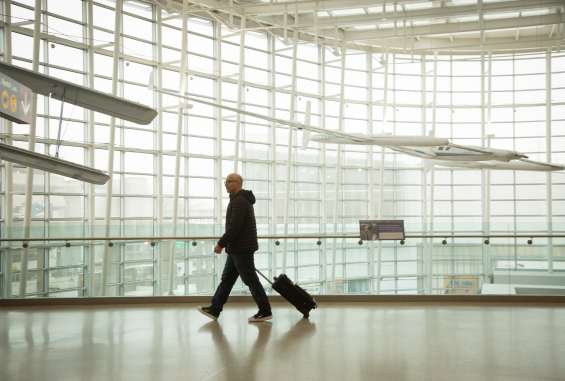 Man dressed in black alone walking through bright white airport