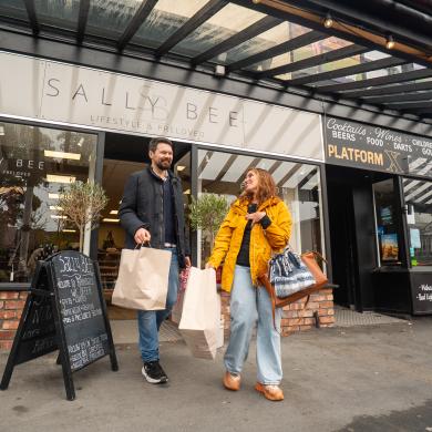 A couple leave a lifestyle shop carrying shopping bags.