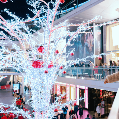People walking around Liverpool one shopping centre at night with Christmas lights and shops in the background.
