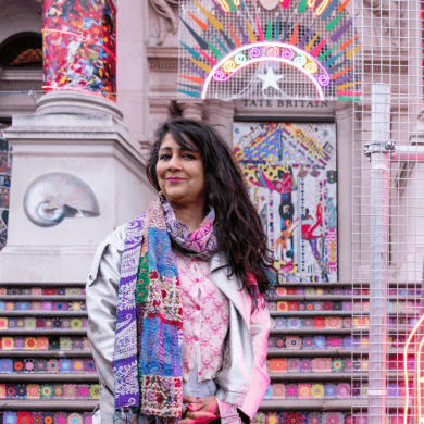 Artist Chila Burman stood in front of an installation made of neon lights at the Tate Britain.