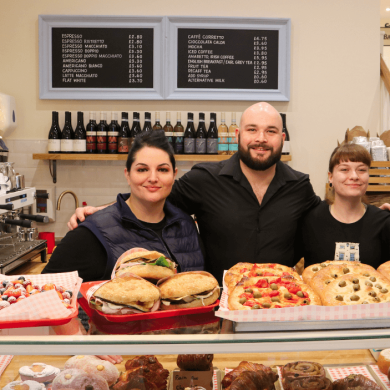 Four people stood behind a counter with baked goods on the top