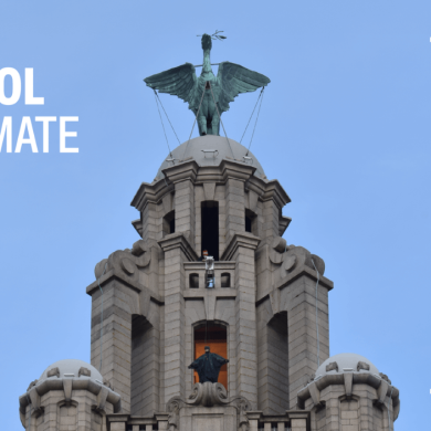 The top of the Royal Liver Building with the Liver Bird at the top. Someone dressed as The Batman is stood on a platform as they are filmed for a movie.